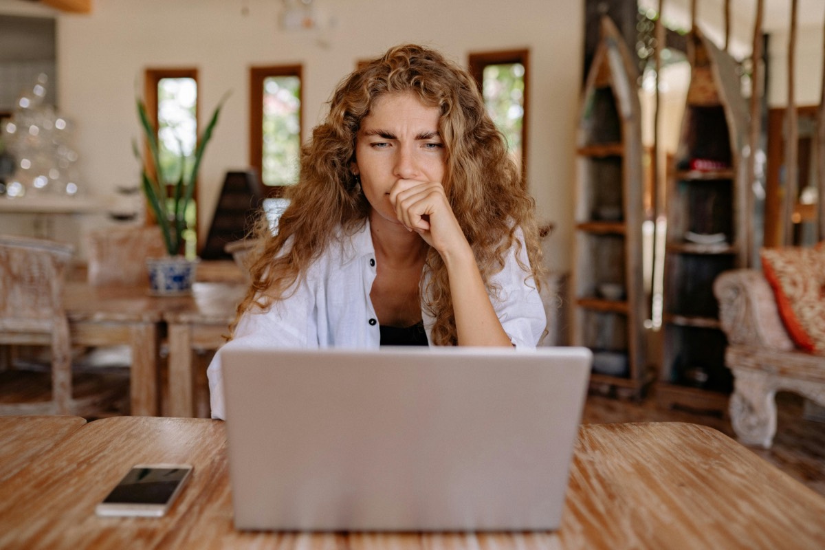 Woman thinking while looking at her laptop screen